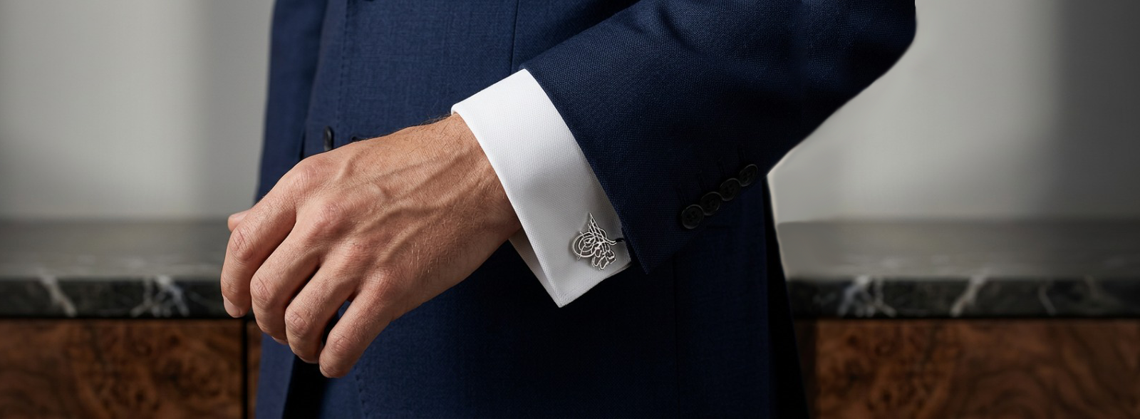 A sophisticated close-up of a man wearing elegant 925 sterling silver cufflinks with a tailored suit, reflecting luxury craftsmanship and timeless style for men by Saad of Egypt.