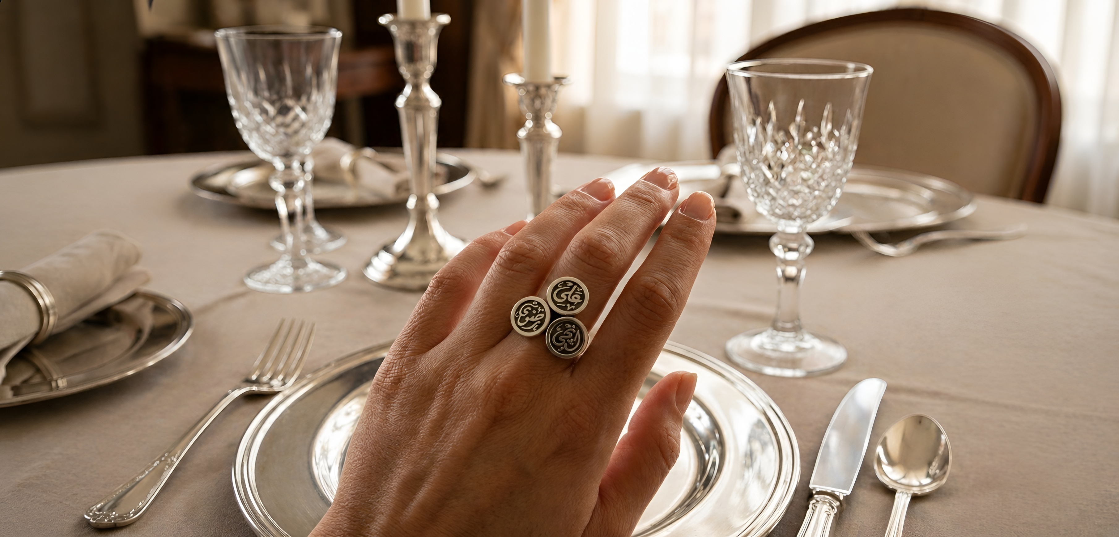 Close-up of a woman wearing customized sterling silver rings on a dining table, showcasing personalized jewelry design and refined craftsmanship by Saad of Egypt.